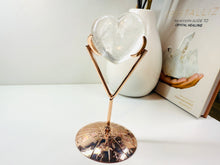 Load image into Gallery viewer, Polished Clear Quartz love heart on rose colored metal stand with zodiac sign