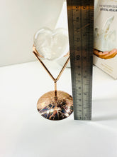 Load image into Gallery viewer, Polished Clear Quartz love heart on rose colored metal stand with zodiac sign