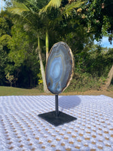 Load image into Gallery viewer, Natural polished Agate slice on black stand with gold electroplating around the edges